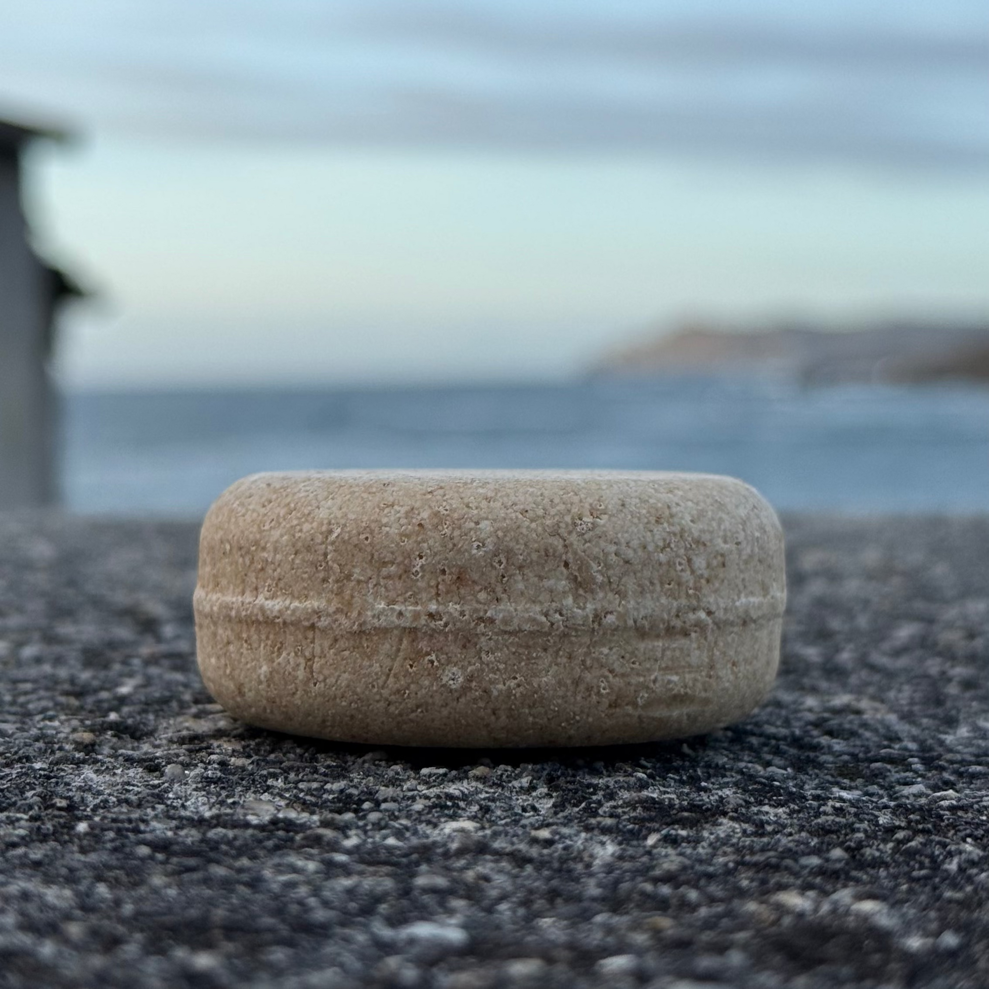 imagen del contorno del champu para cabellos grasos de amodinho champu solido natural con el mar de beo al fondo